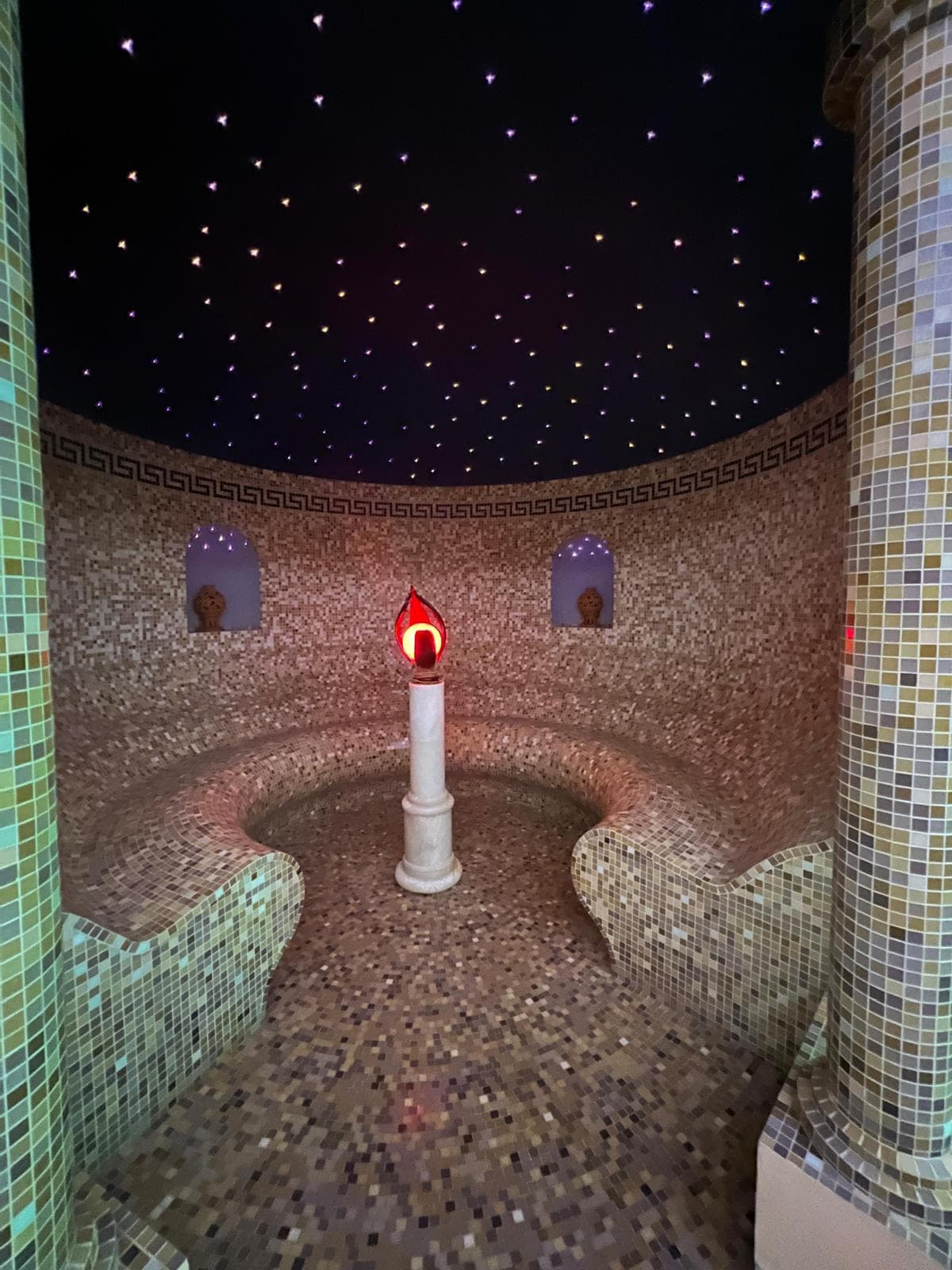 Calidarium rivestito in mosaico con sedute curve, luci a soffitto e lampada centrale