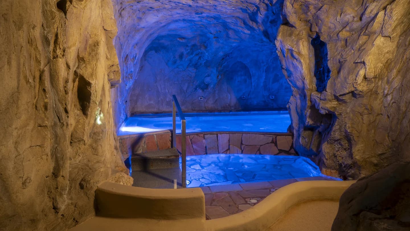 Vasca idromassaggio inserita in un ambiente roccioso con acqua illuminata di blu
