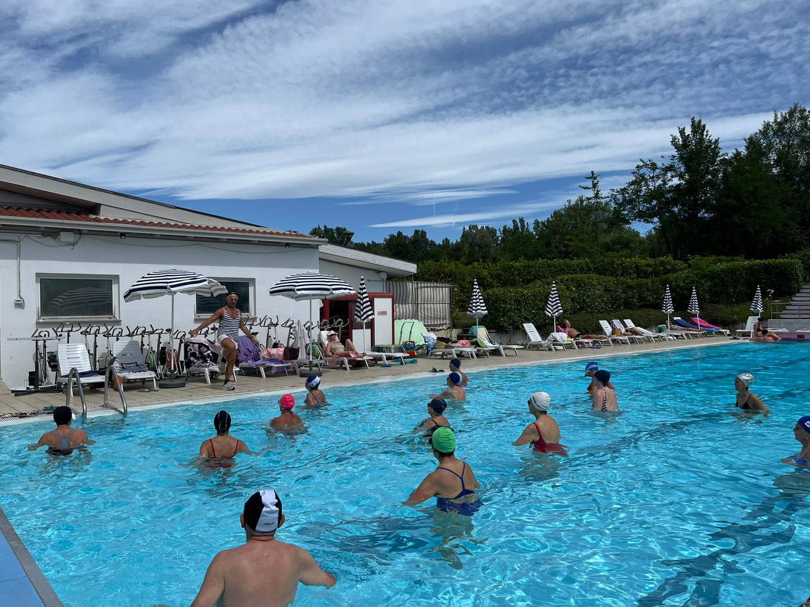 Lezione di acquafitness in piscina con istruttrice e partecipanti in acqua