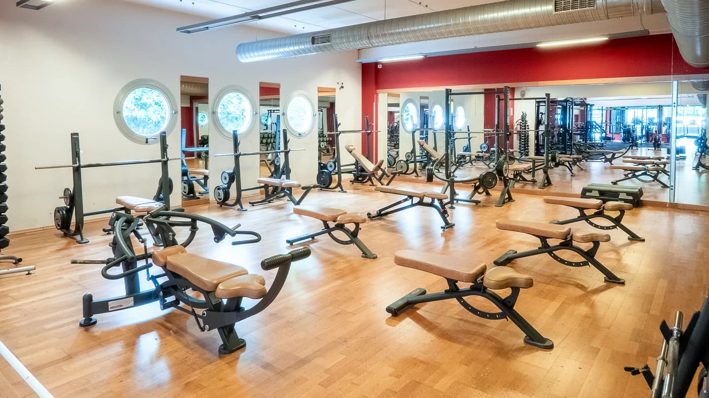 Sala pesi New Way Fitness con panche, bilancieri, specchi e pavimento in legno